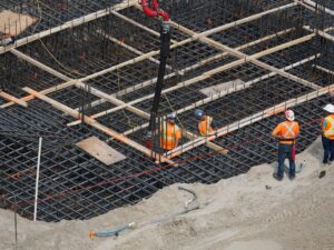 High angle view of construction workers reinforcing a steel foundation at a building site.